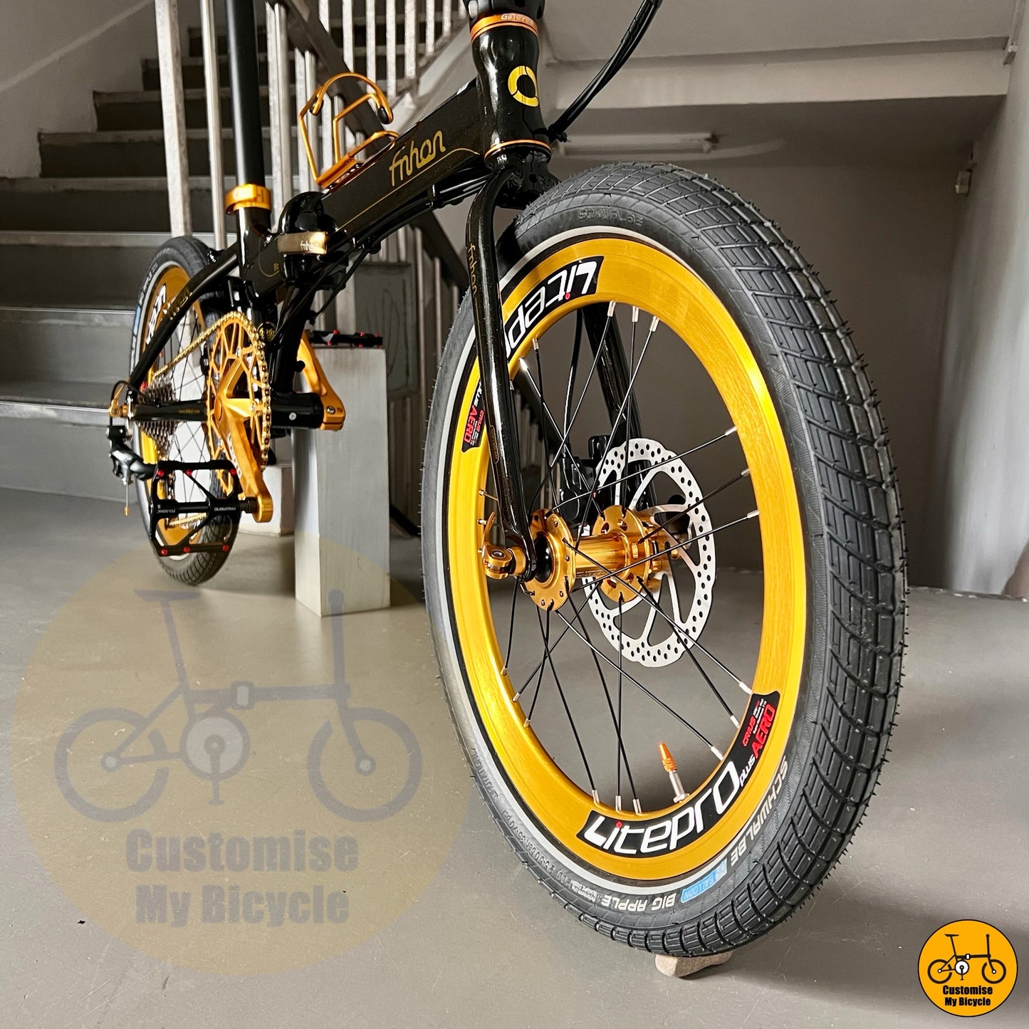 Black and yellow bicycle with 'Customise My Bicycle' branding on a staircase background