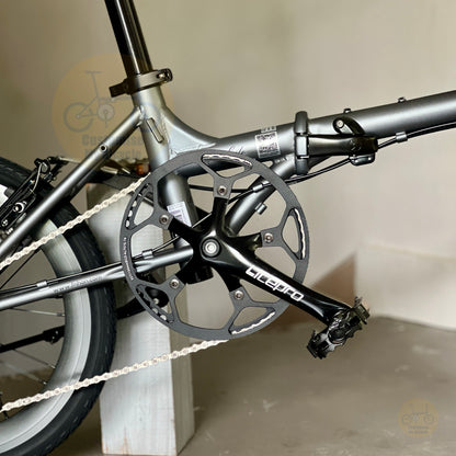 Close-up of a folding bicycle crankset with a black chainring and black pedal arm, attached to a matte gray frame. The brand name 'LIFETO' is visible on the crank arm.