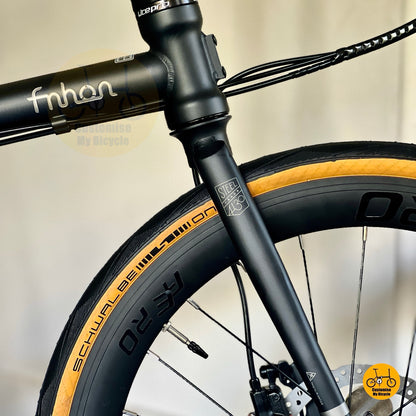 SCHWALBE tan wall tyres on matte black folding bicycle  
